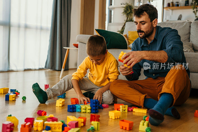 父亲和儿子在客厅的地板上玩立方体。