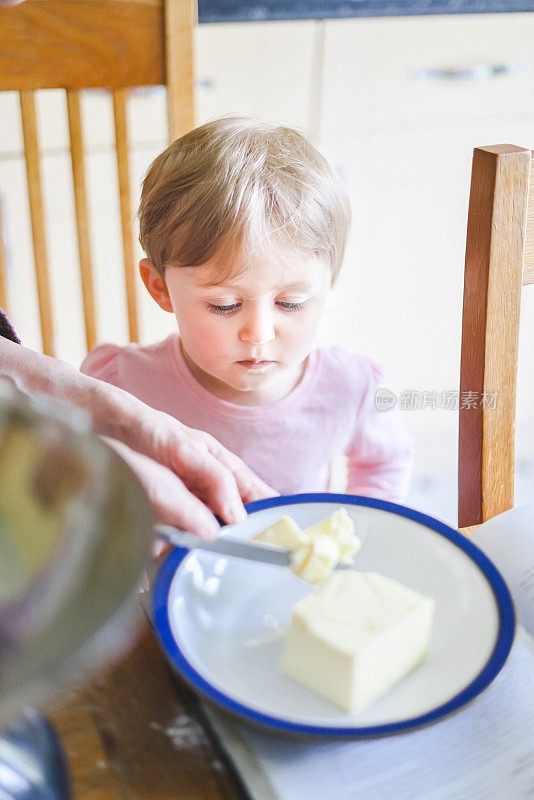 奶奶在厨房的桌子上教她的孙子如何准备蛋糕混合物