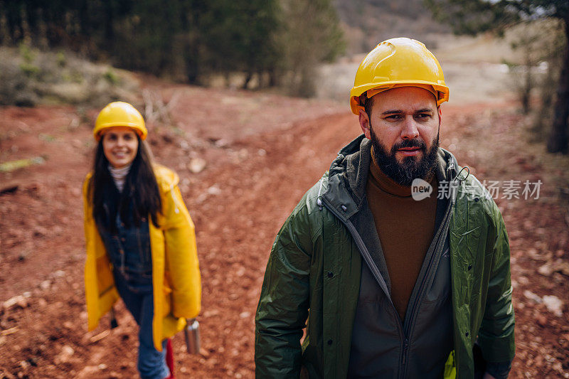 两个年轻的工程师走在森林的道路上