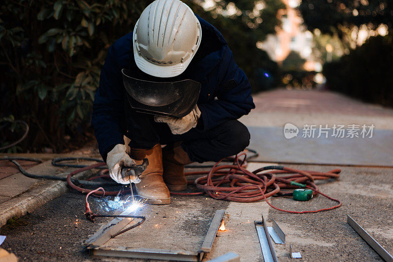 一名中年男性工人正在使用切割机和焊机