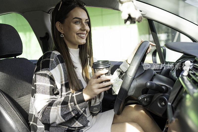 快乐的年轻女子在车里喝外卖咖啡