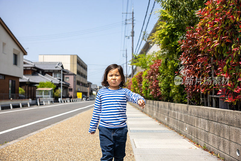 自信的小男孩走在住宅区的街道上