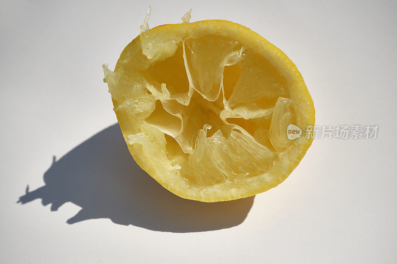在强烈对比明亮的光线下，白色背景下的半个柠檬。
