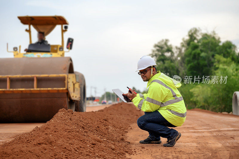 亚洲土木工程师检查道路施工改善基地道路施工红土。振动压路机附近各层红土填埋检查。