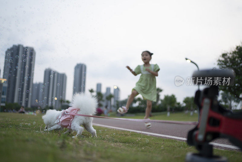 小女孩和她的宠物狗玩彩色泡泡