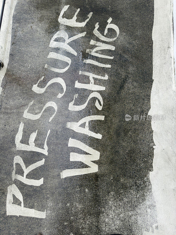 用压力洗衣机在肮脏的水泥地上写压力清洗