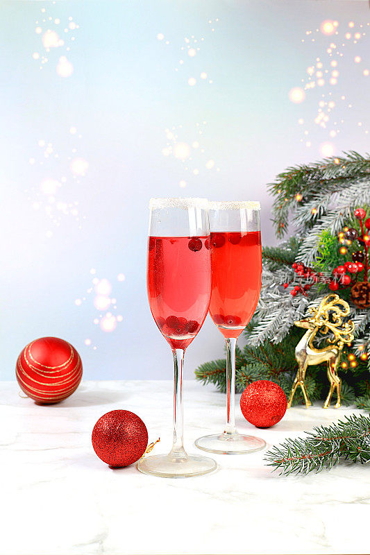 圣诞酒精鸡尾酒配红香槟，含含水鸡尾酒配蔓越莓杯，以冷杉树枝和装饰为节日背景，酒吧概念，派对上的酒精饮料，