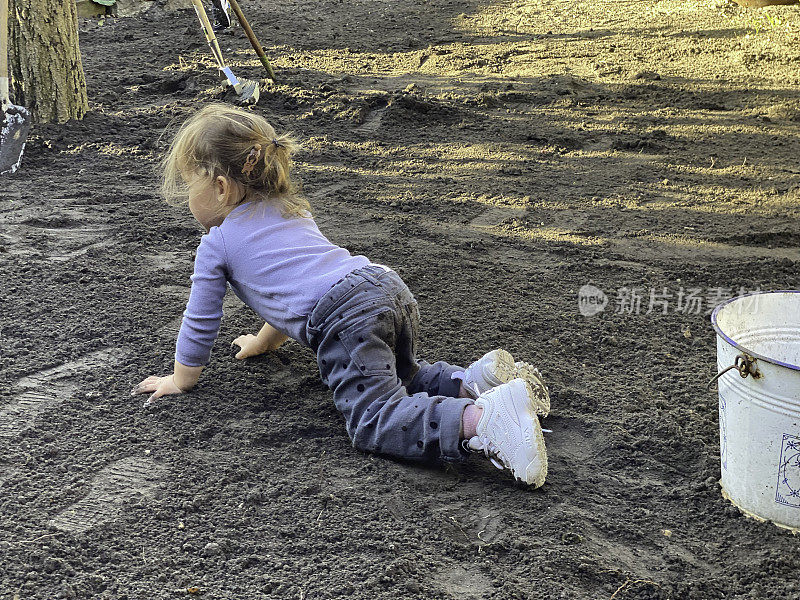 蹒跚学步的女孩在花园里干活