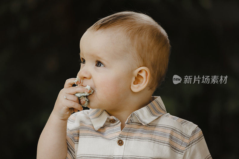 一岁的小男孩在吃他的生日蛋糕