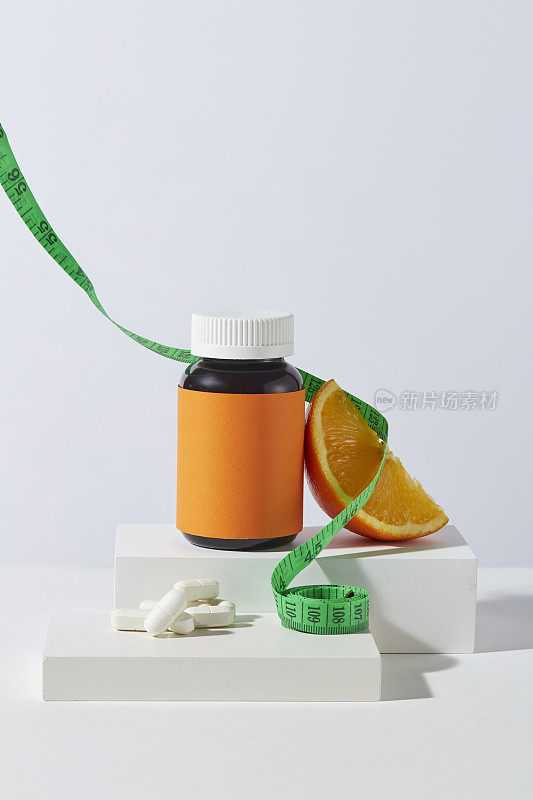 有机减肥药广告提取自橙色成分，空白瓶和橙色片在白色的讲台上呈现白色的纹理。前视图，为文本留出空间