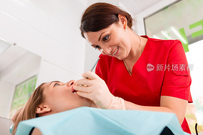 一位女牙医正在检查她的病人是否有龋齿。这个女孩会照顾牙齿的健康。美丽，牙齿健康，呵护牙齿。