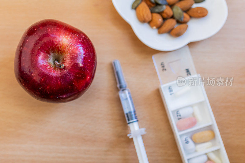 不同的药丸在塑料日常用品和治疗糖尿病的补救措施。健康零食，苹果，杏仁和南瓜子。