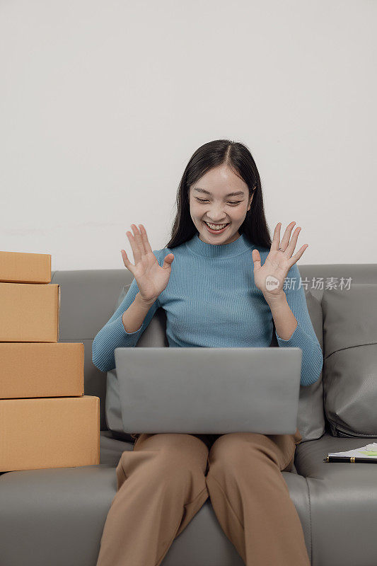 邮包，网上销售概念中小企业创业。一个穿着围裙的独立亚洲女性的小企业主用笔记本电脑和盒子在网上接受订单。中小企业业务。