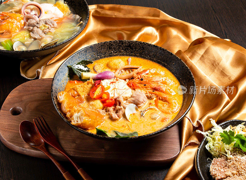 海鲜和鸡肉用叉子和勺子炖在盘子里，在木板上隔离，亚洲食物的侧视图