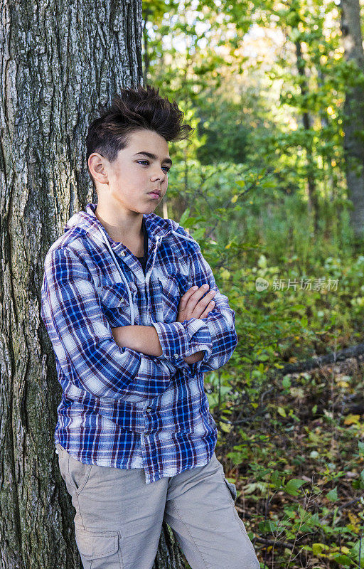 英俊的青春期前男孩在森林里严肃而沉思。