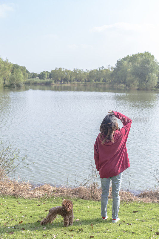 一个女人和她的小狗在湖边玩耍