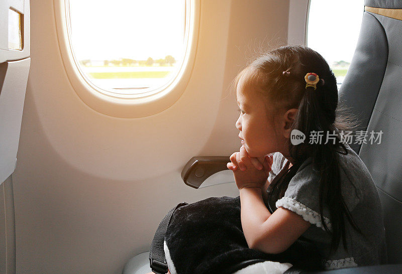 小女孩坐在飞机上，靠窗祈祷。可爱的小女孩乘飞机旅行。