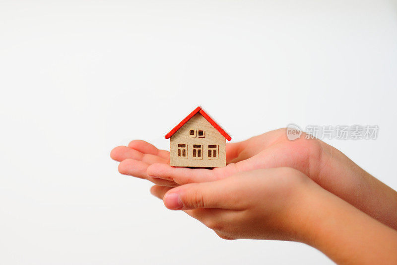 孩子的手握模型的房子在白色的背景。采用概念。