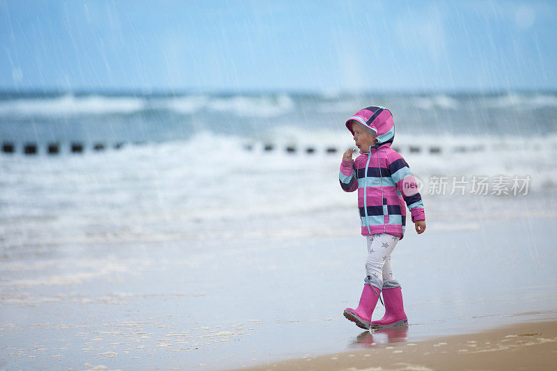 小女孩在雨中漫步在波罗的海的海滩上