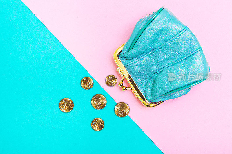 钱包里的硬币。一个皮革钱包，钱包上的几何粉色和绿松石背景。趋势的颜色。