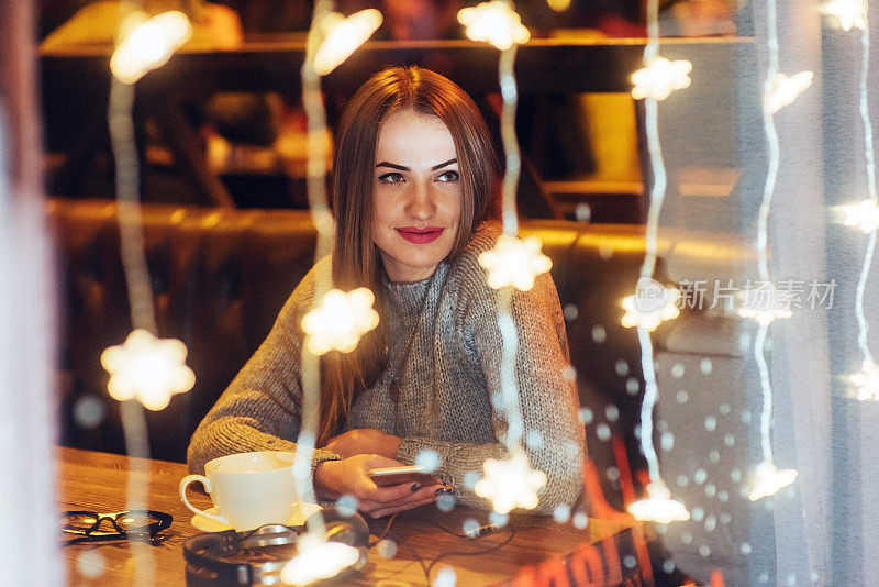 年轻漂亮的女人坐在咖啡馆里，喝着咖啡。圣诞节、新年、情人节、寒假概念