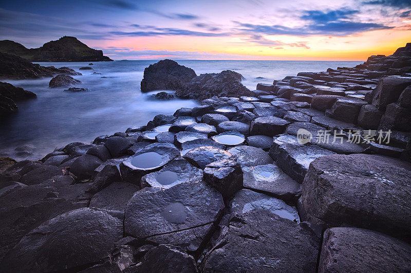 英国北爱尔兰安特里姆郡巨人堤道的岩石形成日落