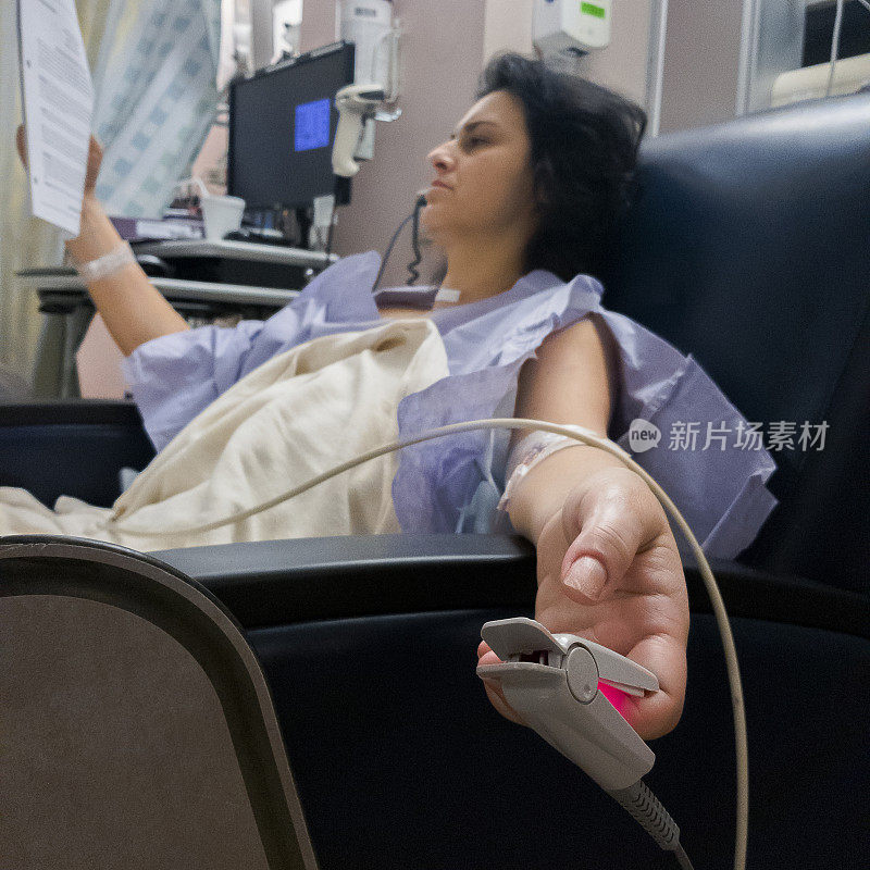 迷人的成熟的术后女性在医院休息后阅读医学论文。
