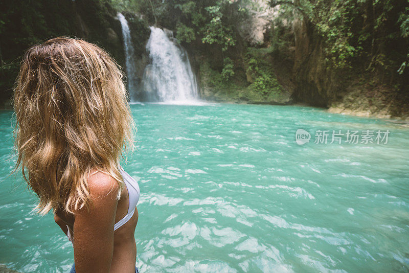 年轻女子凝视着美丽的瀑布