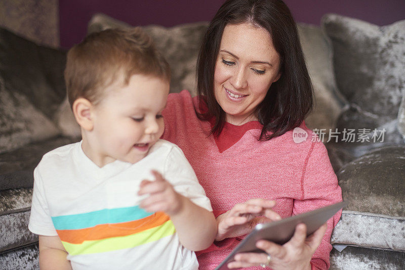 母亲和幼童使用数字平板电脑