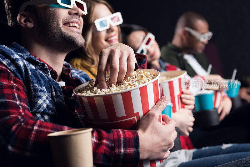年轻的朋友们戴着3d眼镜在电影院吃爆米花看电影