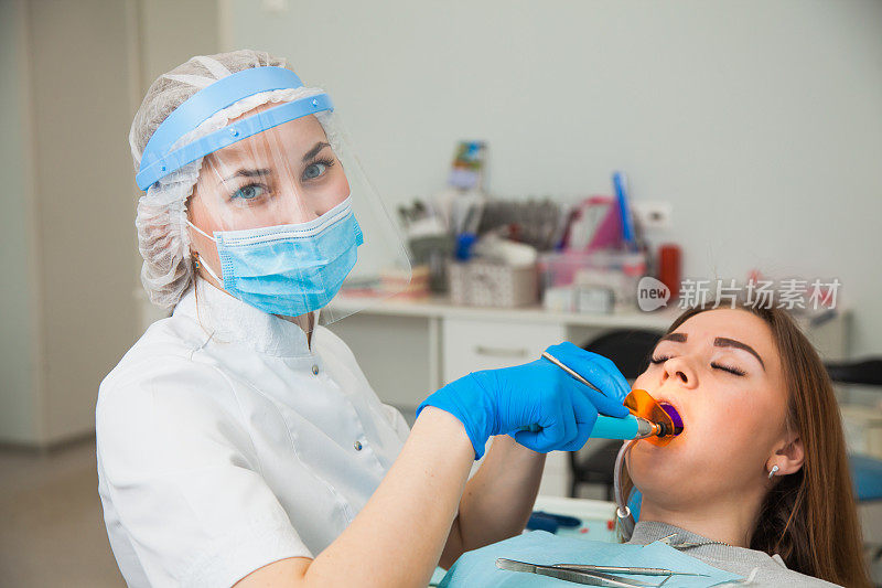 女牙医工作与光固化密封，病人龋齿在椅子上。