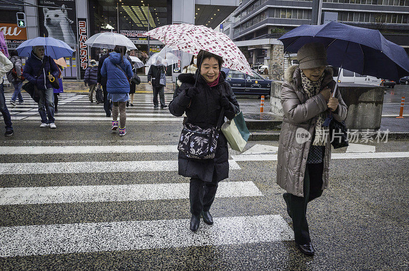 在日本的雨天，东京妇女撑着雨伞过马路