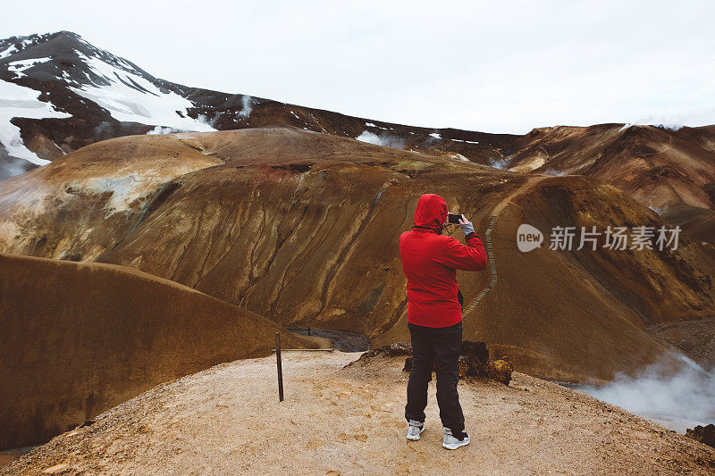 一名身穿红色夹克的男子在拍摄Kerlingarfj?ll冰岛火山景观