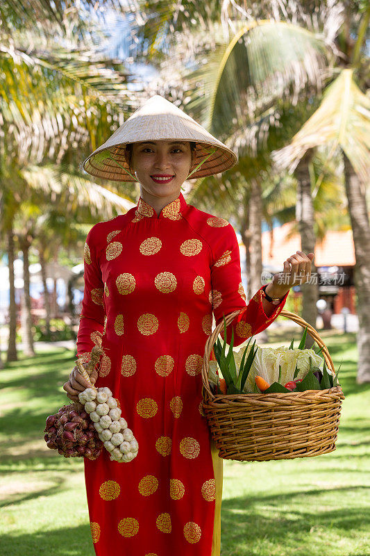 异国传统越南女孩拿着各种热带水果篮子