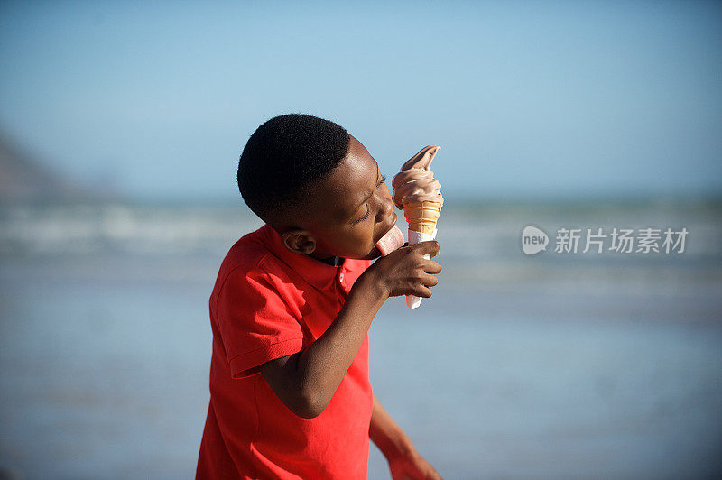 男孩在海滩上舔冰淇淋舌头