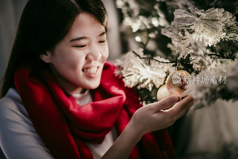 一位庆祝圣诞节的亚裔华人女性装饰圣诞树