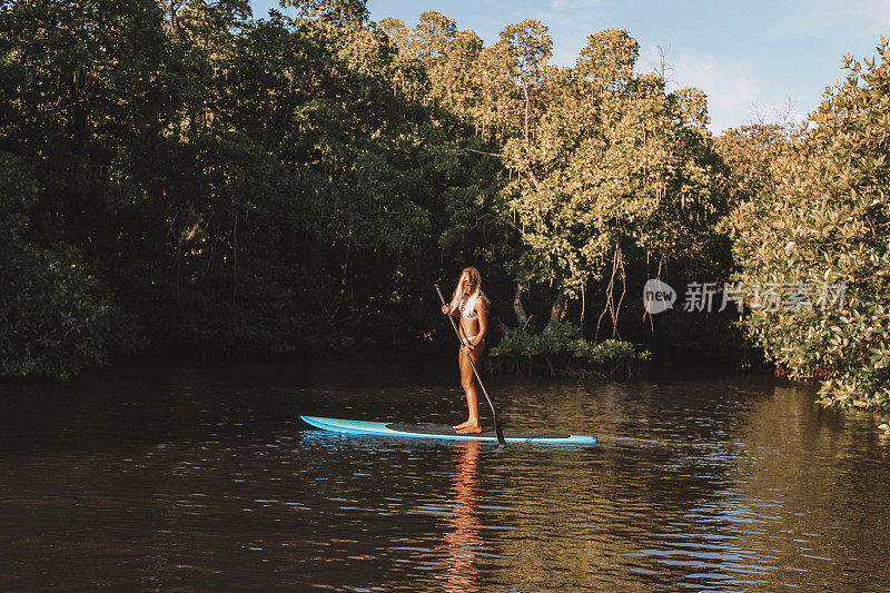 女人站着在海里划桨