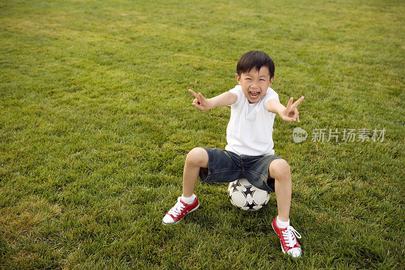 小男孩在草地上踢足球