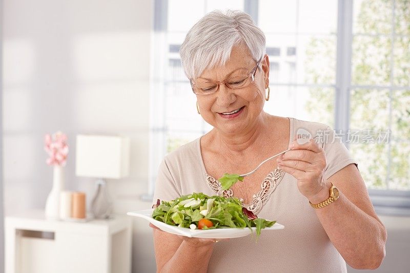 老妇人在吃绿色沙拉