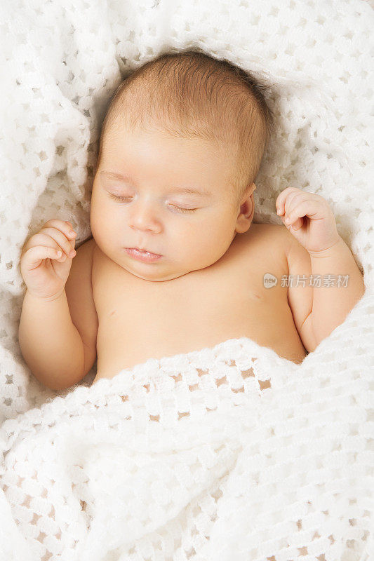 新生儿睡在白色的毛毯上
