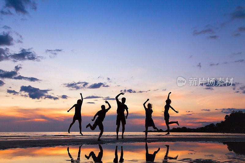 日落时分，一群快乐的人在海滩上跳跃