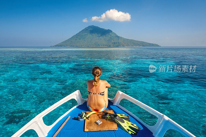 穿着泳衣的年轻女子坐在船上面罩和脚蹼上