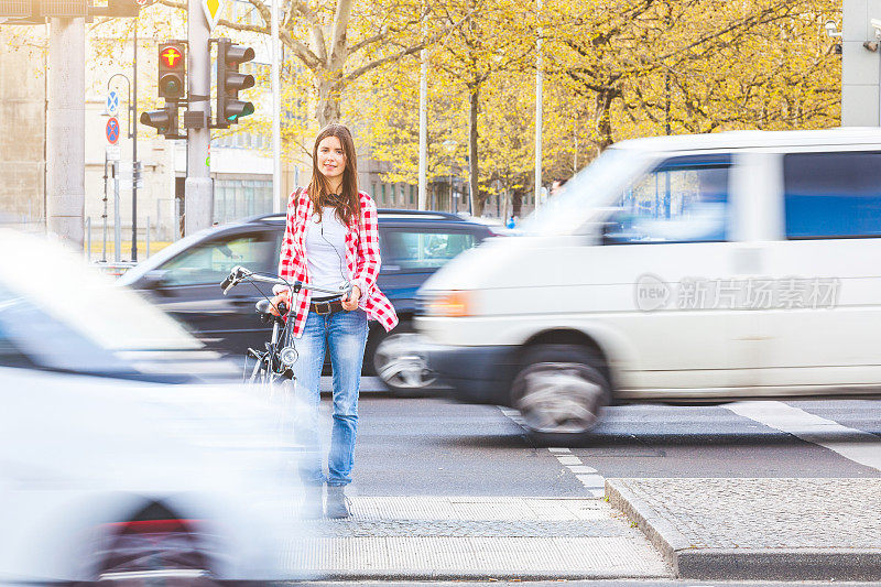年轻女子骑着自行车等着过马路