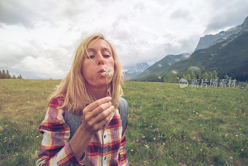 一位年轻的女子正在向空中播撒蒲公英的种子