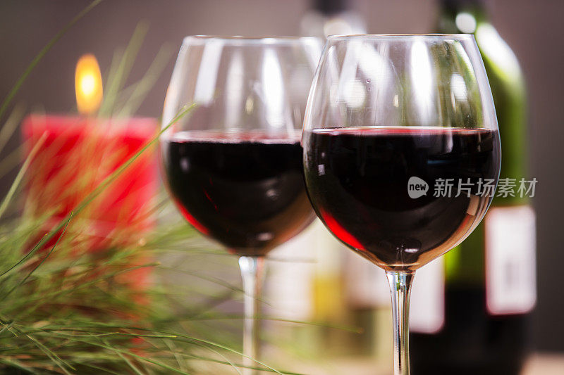 两杯红酒，玻璃杯，瓶子和蜡烛。松树树枝。圣诞节。