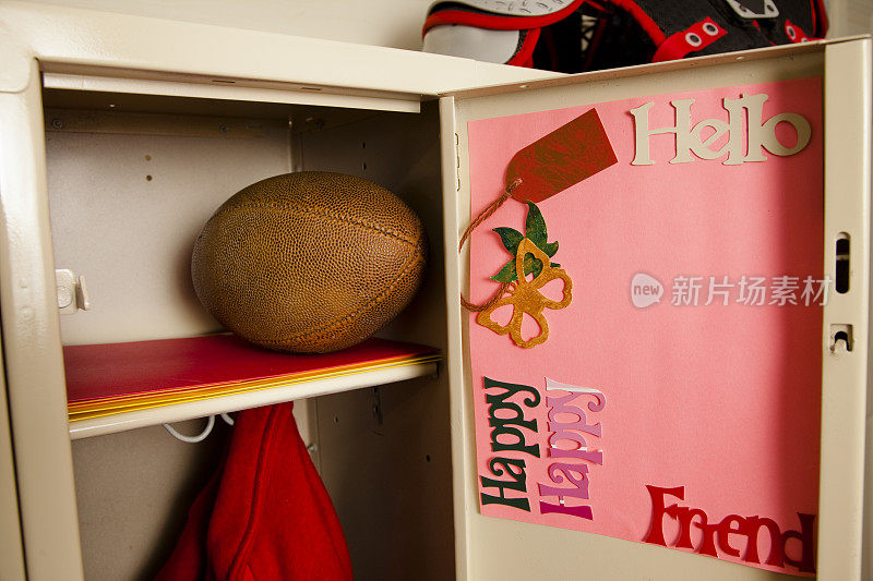 橄榄球，夹克放在学校储物柜里。笔记的门。