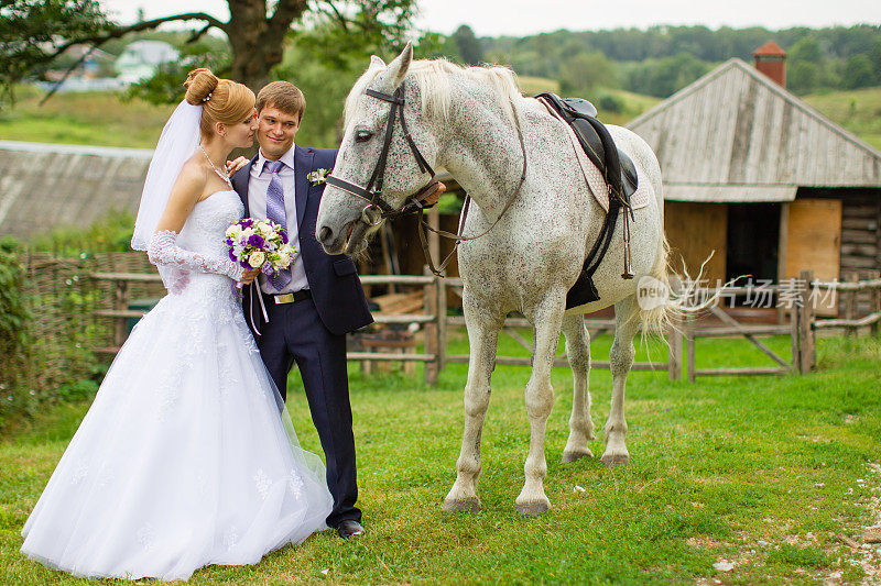 新婚夫妇在农场附近放牧的马