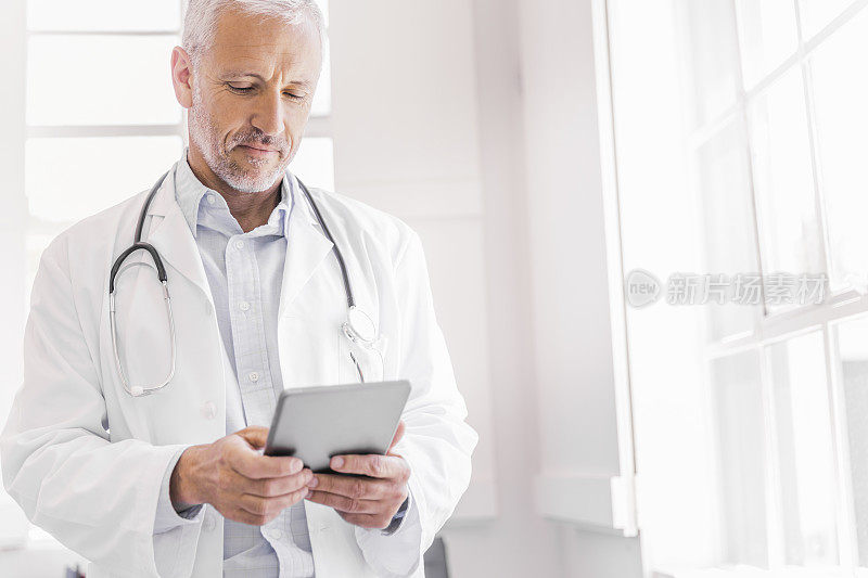 医生使用数字平板电脑在明亮的诊所