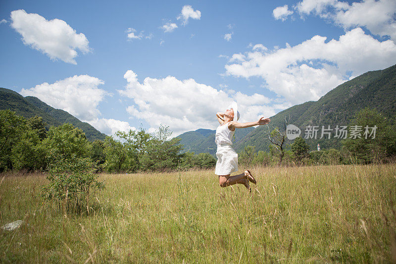 快乐的女人在田野里自由的跳跃