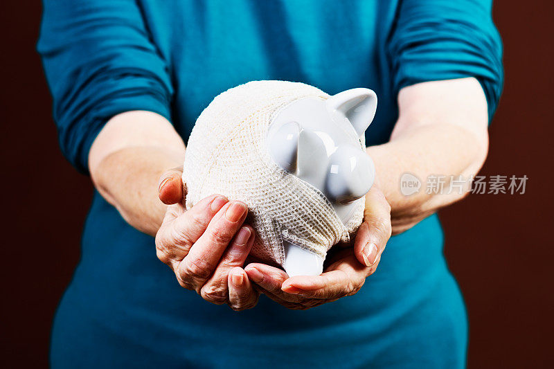 试图保持她的积蓄在一起:手握绷带存钱罐